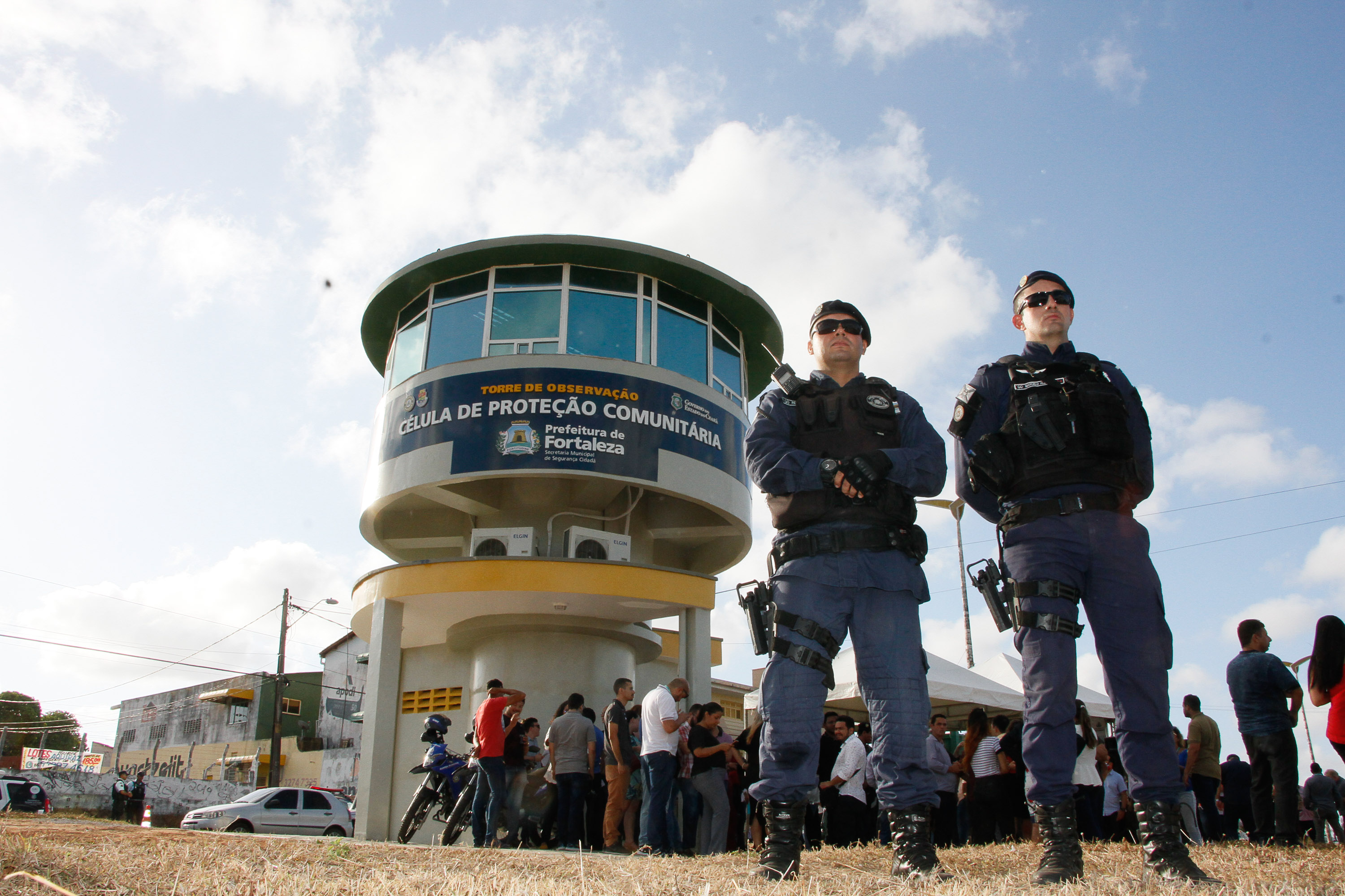 dois guardas municipais em pé e torre de segurança ao fundo